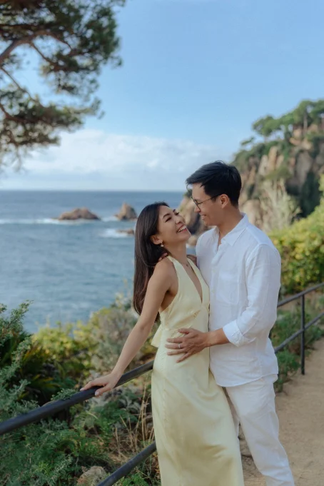 Joyful couple laughing together by the sea at Marimurtra garden, captured during a romantic location photoshoot.