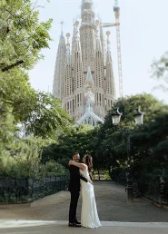 Newlywed couple embraces in front of La Sagrada Familia, capturing a romantic moment with wedding photography.