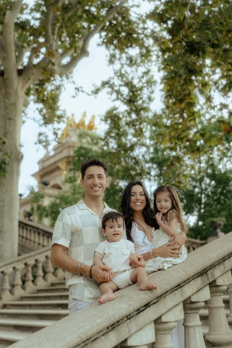 Smiling family enjoys a candid moment on the steps of Park de la Ciutadella during a location portrait session.