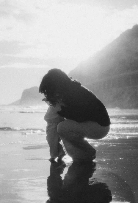 Tender moment between mother and child at Ginesta beach, captured in soft sunlight for a family photography session.