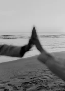 Two hands reach toward each other at sunset on Ginesta beach, capturing a candid moment of connection by the sea.