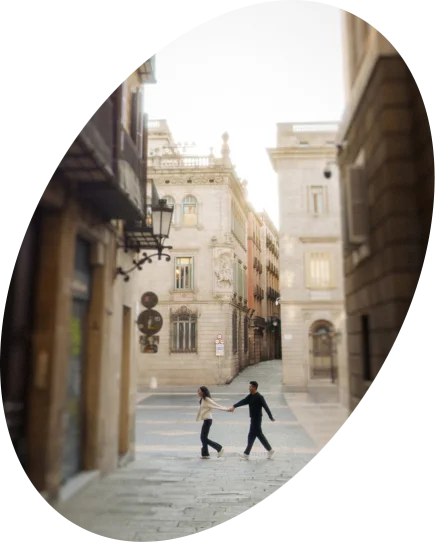 Couple holding hands and laughing while strolling through a charming street in Barcelona, couples photoshoot session.