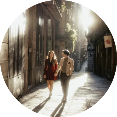 Couple holding hands and smiling while strolling a sunlit street in Barcelona, captured during an engagement photoshoot.