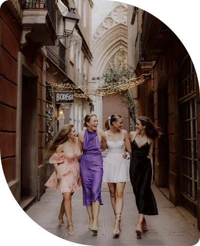 Four friends laughing and walking arm in arm during a Vacation Portraits photoshoot in Barcelona’s Gothic Quarter.