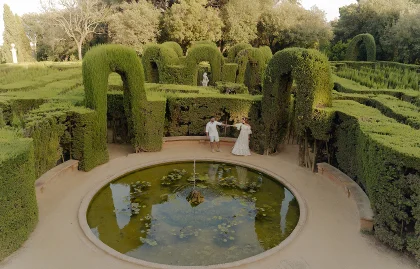 Couple dancing by a tranquil fountain in a lush Barcelona garden, captured during a Vacation Portraits photoshoot.