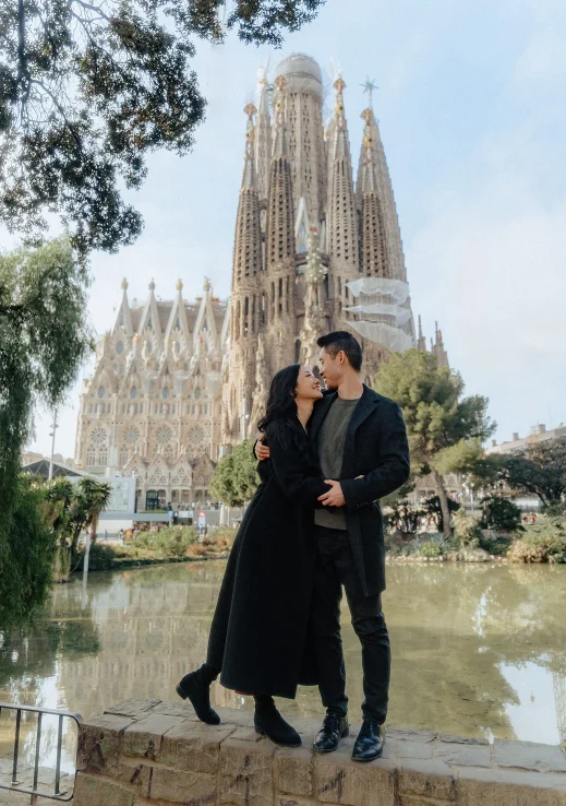 Couple embracing and smiling during a Vacation Portraits photoshoot in front of Sagrada Família, Barcelona.