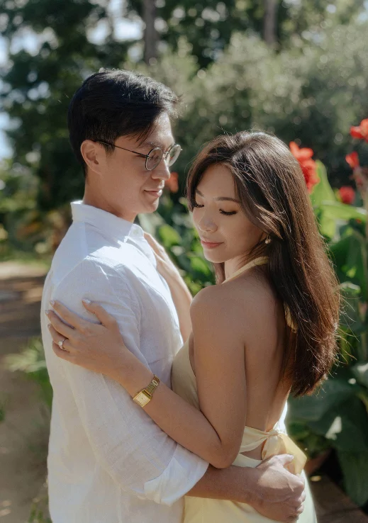 Couple embracing in a sunlit Barcelona garden, capturing a tender moment from a surprise proposal photoshoot.
