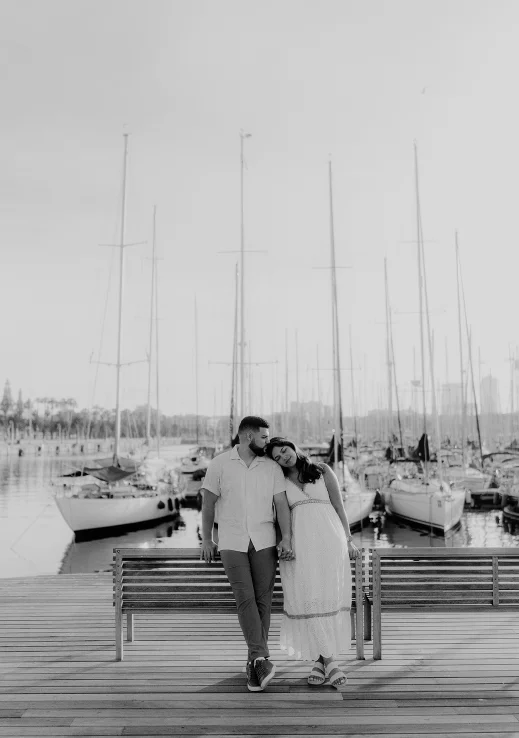 Couple holding hands and sharing a tender moment by the marina during a Vacation Portraits photoshoot in Barcelona.