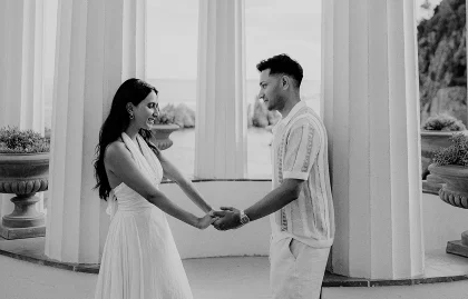 Couple holding hands and smiling during a surprise proposal photoshoot in Barcelona, framed by elegant columns.