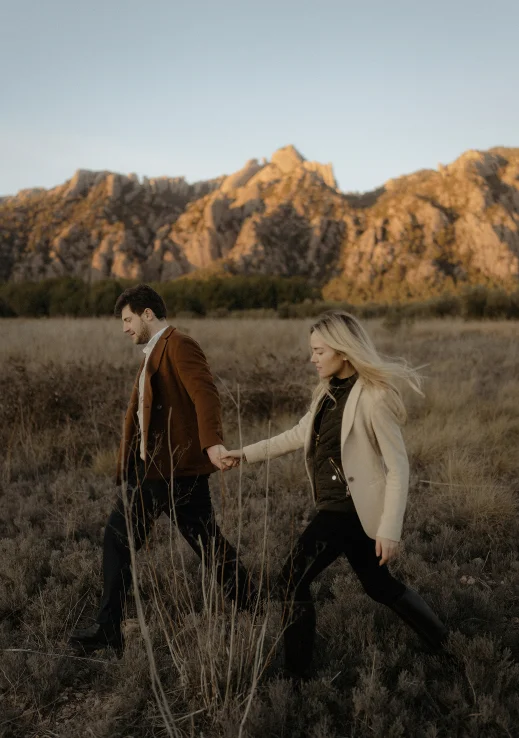 Couple holding hands and walking through a field at sunset, Vacation Portraits photoshoot in Barcelona.
