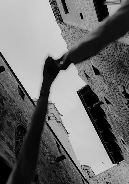Couple holding hands between historic Barcelona buildings, capturing a romantic engagement photoshoot moment.