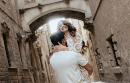 Couple laughing as he lifts her in a romantic Barcelona alley, captured during a Vacation Portraits photoshoot.