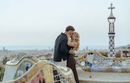 Couple shares a romantic kiss during a surprise proposal photoshoot in Park Güell, Barcelona.