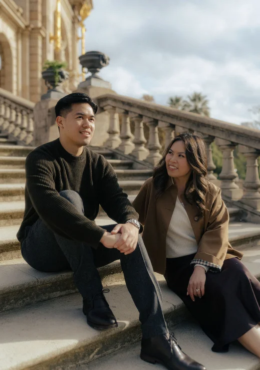 Couple sharing a joyful moment on stone steps during a Vacation Portraits photoshoot in Barcelona.