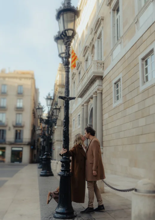Couple sharing a romantic kiss by a lamppost in Barcelona during an engagement photoshoot.