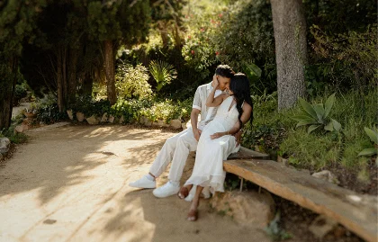 Couple sharing an intimate moment on a park bench during a surprise proposal photoshoot in sunny Barcelona.