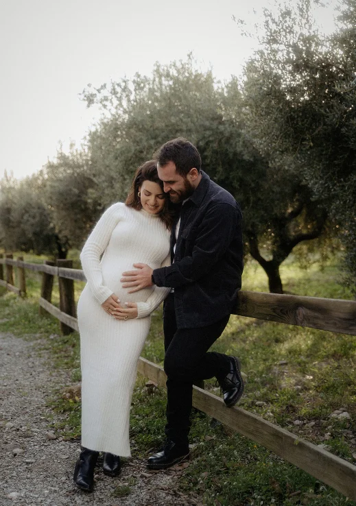 Expectant couple sharing a tender moment during a Vacation Portraits photoshoot in a scenic park in Barcelona.
