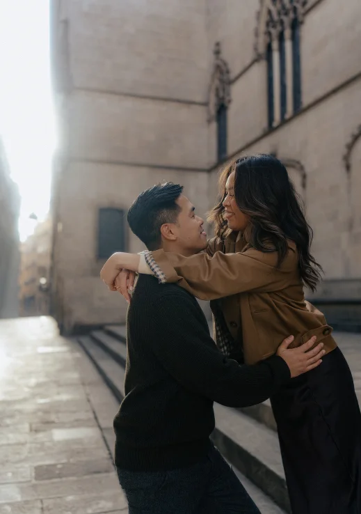 Joyful couple embracing during an engagement photoshoot in the historic streets of Barcelona.