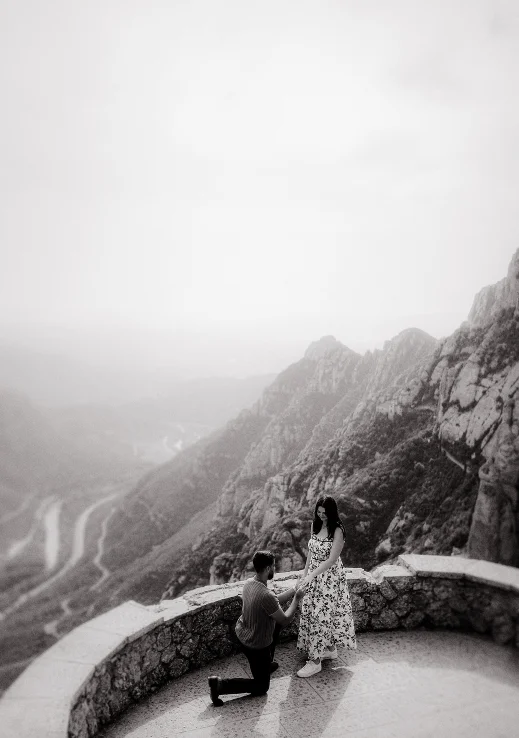 Man proposing to his partner on a scenic Barcelona mountain overlook, capturing a joyful surprise proposal moment.