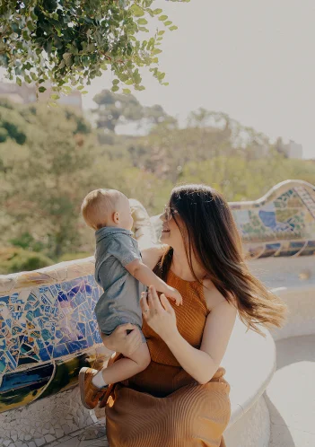 Mother and child share a joyful moment on a mosaic bench during a Vacation Portraits photoshoot in Barcelona.