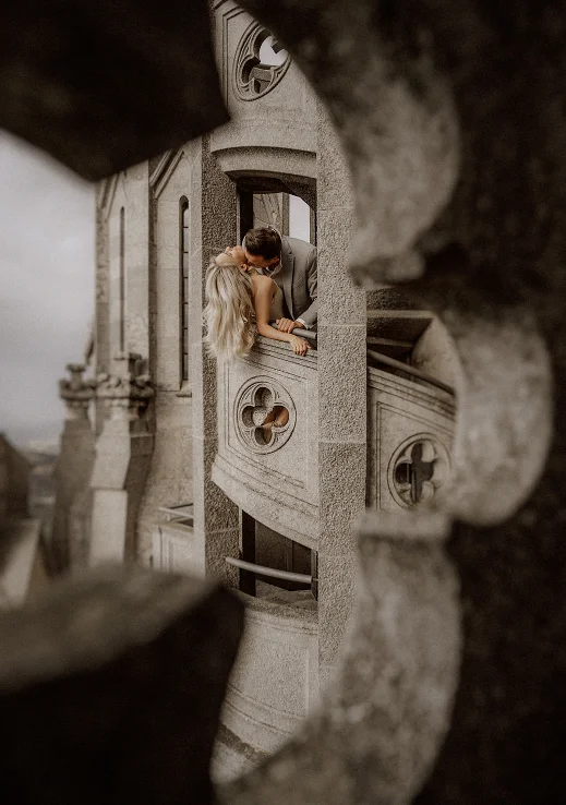 Romantic couple shares a kiss on a stone balcony during a couples photoshoot in Barcelona.
