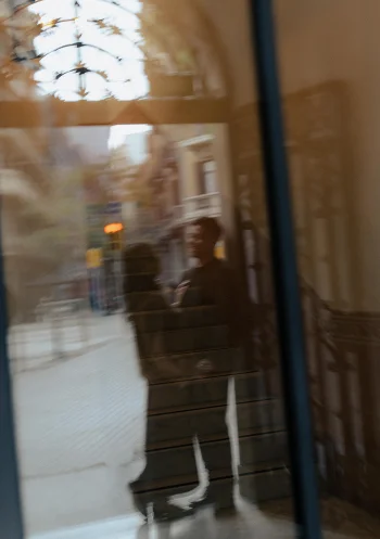 Romantic couple’s reflection in a Barcelona doorway, captured during an engagement photoshoot.