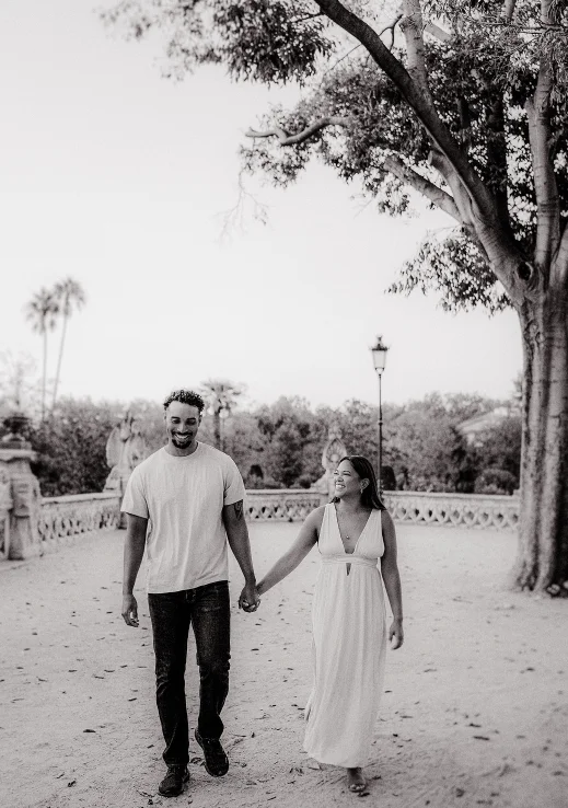 Smiling couple holding hands during a Vacation Portraits photoshoot in a scenic Barcelona park.