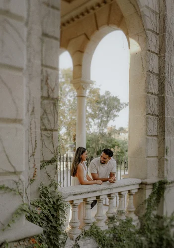 Smiling couple shares a tender moment on a sunlit balcony during an engagement photoshoot in Barcelona.