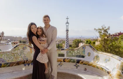 Smiling family embraces during a Vacation Portraits photoshoot in sunny Park Güell, Barcelona.