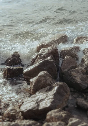 Waves crash against rocky shore in Barcelona, capturing the serene mood of a vacation portraits photoshoot.