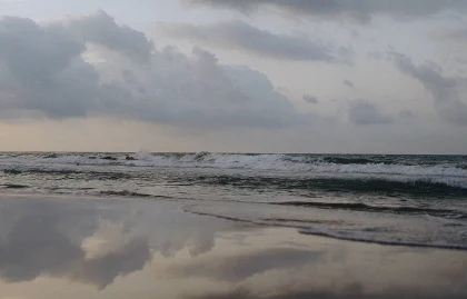 Waves gently rolling onto a quiet Barcelona beach under a moody sky, perfect for romantic engagement shoots.