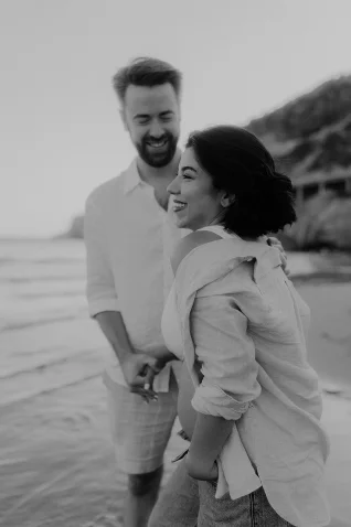 Couple laughing together on a Barcelona beach, captured during a Vacation Portraits photoshoot.