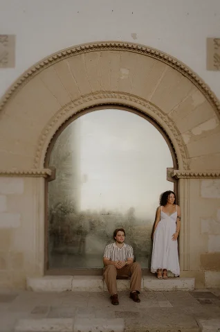 Couple posing in front of an arched window in Barcelona, capturing a relaxed engagement photoshoot moment.