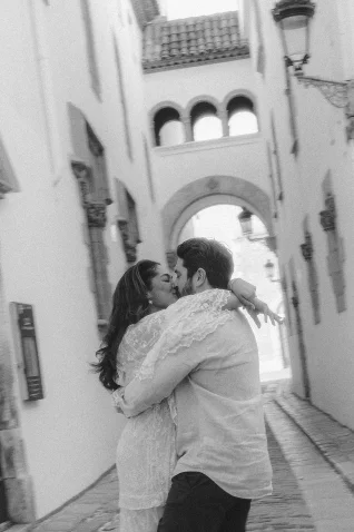 Couple shares a joyful kiss in a charming Barcelona alley during a surprise proposal photoshoot.