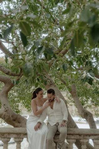 Couple shares a tender moment under lush trees during a Vacation Portraits photoshoot in Barcelona.