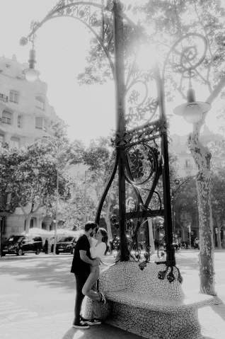 Couple sharing a romantic moment on a mosaic bench in Barcelona, perfect for an engagement photoshoot session.