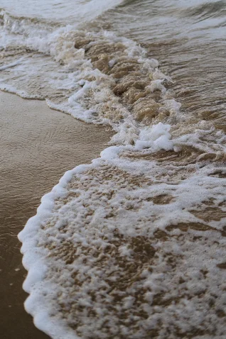 Gentle waves wash over the sandy shore at Barcelona beach, capturing a tranquil moment in natural light.