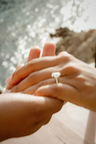 Hands gently held, engagement ring sparkling, capturing a surprise proposal photoshoot in Barcelona by the sea.