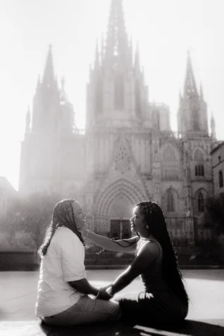 Joyful couple shares a tender moment during a surprise proposal photoshoot in front of Barcelona Cathedral.