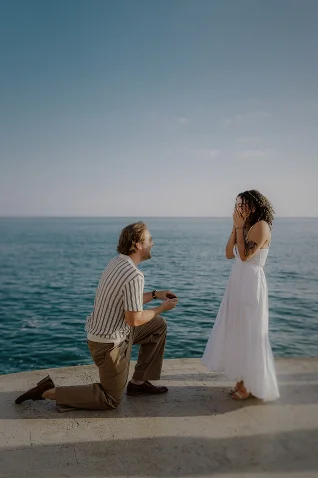 Man proposing to his surprised partner by the sea in Barcelona, captured during a surprise proposal photoshoot.