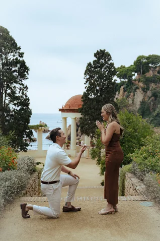 Man proposing to his surprised partner in a romantic Barcelona garden, captured during a surprise proposal photoshoot.