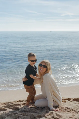 Mother and son share a joyful moment on a sunny Barcelona beach, captured during a vacation portraits photoshoot.