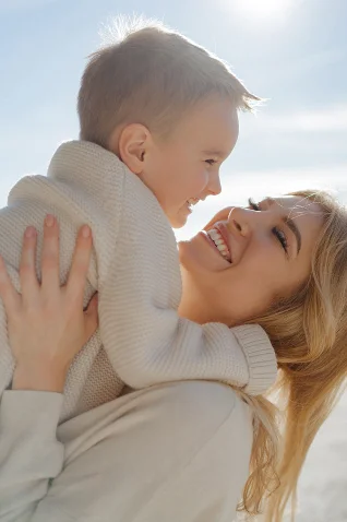 Mother lifts her smiling son during a sunny Vacation Portraits photoshoot in Barcelona, capturing pure joy and connection.