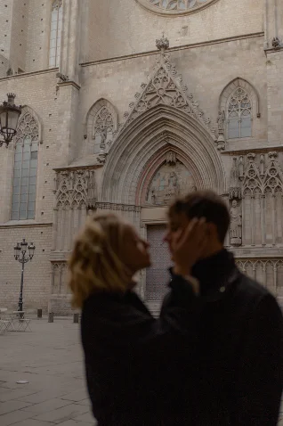 Romantic couple shares an intimate moment during an engagement photoshoot in front of a Barcelona cathedral.