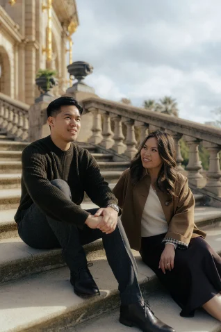 Smiling couple enjoying a relaxed moment on historic steps during a Vacation Portraits photoshoot in Barcelona.