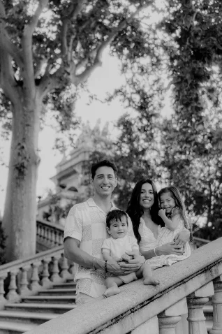 Smiling family poses on a grand staircase in Barcelona during a Vacation Portraits photoshoot, radiating joy and togetherness