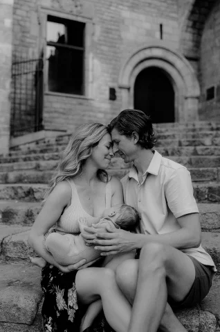 Young couple shares a tender moment with their baby on stone steps during a Vacation Portraits session in Barcelona.