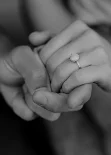 Close-up of a couple holding hands, showing an engagement ring during a surprise proposal photoshoot.