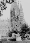 Couple embraces on a bench in front of Sagrada Familia, captured during a romantic engagement photoshoot in Barcelona.