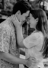Couple embraces with joyful smiles during a surprise proposal photoshoot, capturing a heartfelt moment outdoors.